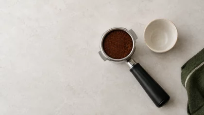 Porte-filtre rempli de café finement moulu près d’une tasse d’expresso